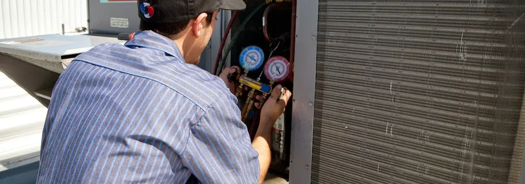 HVAC technician servicing a condenser unit in Elyria